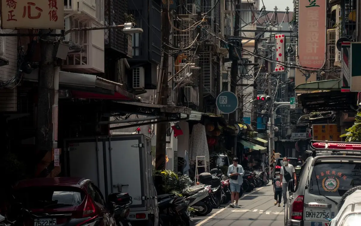 Bustling urban street with scooters, cars, and vibrant signa